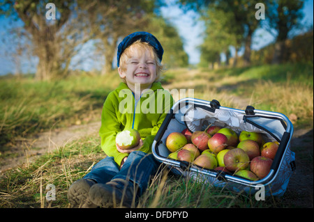 Deutschland, Sachsen, junge mit Korb voller Äpfel, sitzt lächelnd Stockfoto