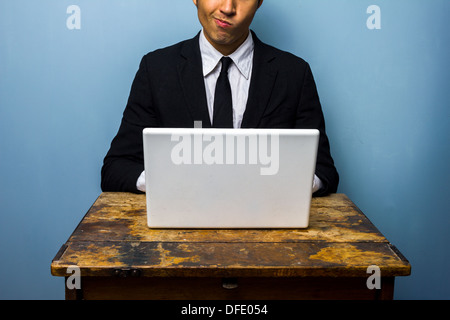 Verwirrter jungen Geschäftsmann nutzt seinen Laptop auf einem alten Schreibtisch Stockfoto