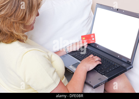 Eine Frau mit ihrem Laptop-Computer, geben Sie ihre Kreditkarten-Daten für einen Online-Kauf Stockfoto