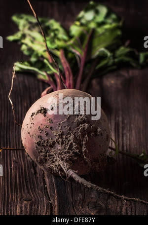 Rote Beete mit Erde auf hölzernen Hintergrund Stockfoto