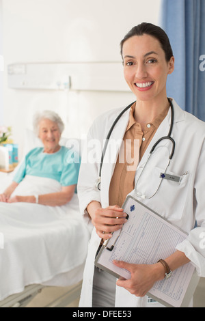 Porträt von lächelnden Arzt mit älteren Patienten im Hintergrund Stockfoto