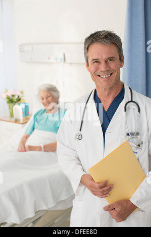 Porträt von lächelnden Arzt mit Patienten im Hintergrund Stockfoto