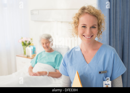 Porträt von lächelnden Krankenschwester mit älteren Patienten im Hintergrund Stockfoto