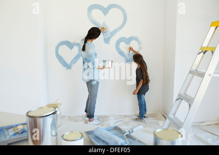 Mutter und Tochter Malerei blauen Herzen auf Wand im neuen Haus Stockfoto