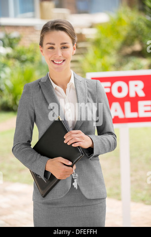 Porträt eines lächelnden Immobilienmakler in der Nähe von For Sale Schild