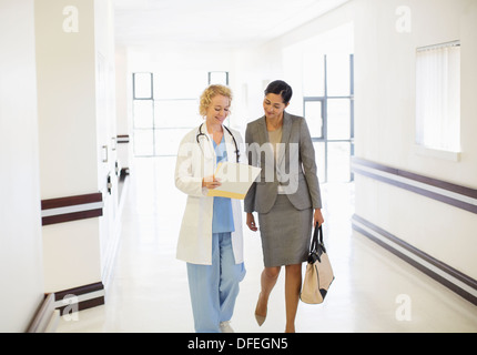 Arzt und Geschäftsfrau im Krankenhausflur sprechen Stockfoto