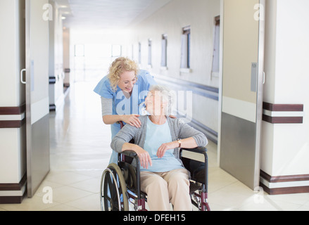 Krankenschwester mit alternden Patienten im Rollstuhl im Krankenhausflur Stockfoto