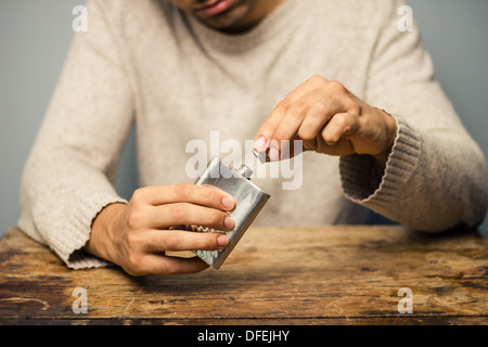 Junger Mann sitzt an einem Tisch mit einem Kolben in seinen Händen Stockfoto