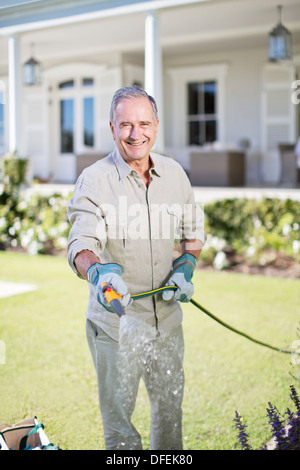 Senior woman Bewässerung von Pflanzen im Garten Stockfoto