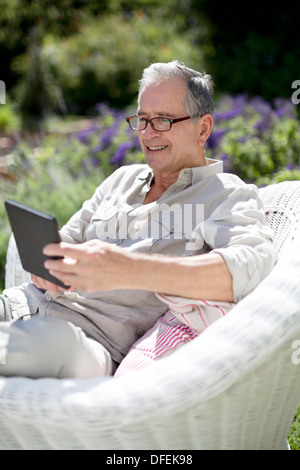 Senior woman mit digital-Tablette in Sessel Stockfoto