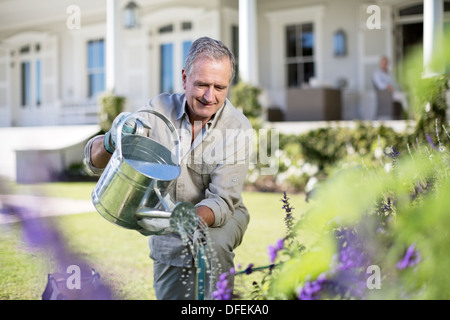 Senior woman Bewässerung von Pflanzen im Garten Stockfoto