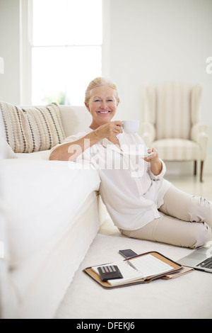 Ältere Frau Kaffeetrinken am Boden des Wohnzimmers Stockfoto