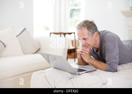 Ältere Mann mit Laptop im Wohnzimmer Stockfoto