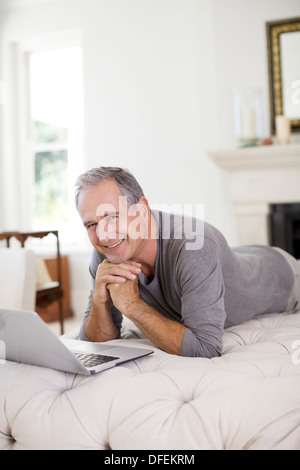 Ältere Mann mit Laptop im Wohnzimmer Stockfoto