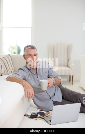 Ältere Mann mit Laptop am Boden des Wohnzimmers Stockfoto