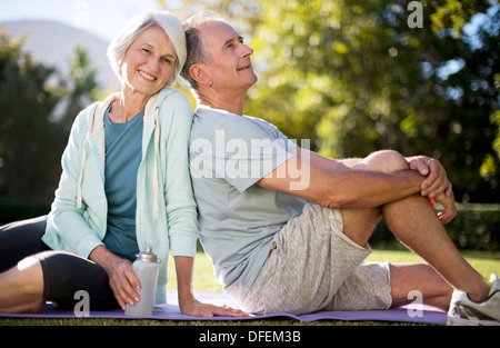 Älteres Paar auf Yoga-Matte im Park sitzend Stockfoto