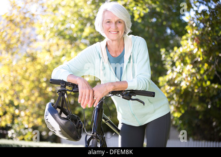 Porträt von senior Frau stützte sich auf dem Fahrrad Stockfoto