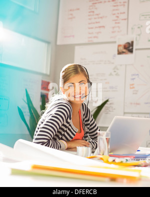 Geschäftsfrau tragen Kopfhörer am Schreibtisch im Büro Stockfoto