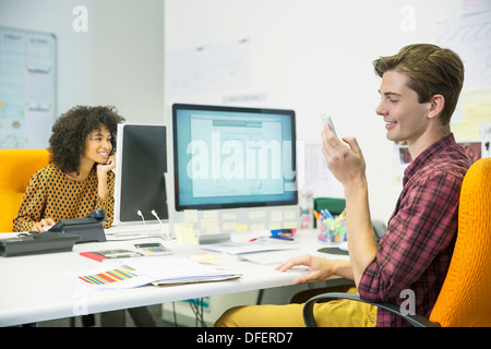 Geschäftsmann mit Handy am Schreibtisch im Büro Stockfoto