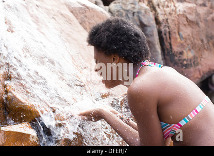 Frau spielt im Wasserfall Stockfoto