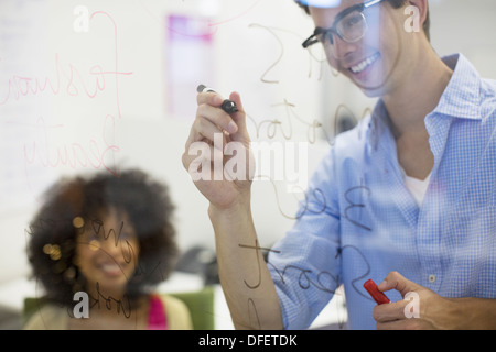 Business-Leute, die schreiben auf Glas im Büro Stockfoto