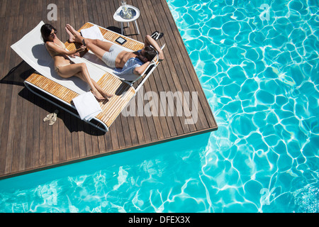 Paar Handauflegen Liegestuhl am Pool Stockfoto