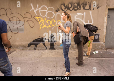 New York, USA. 3. Oktober 2013. Graffiti-Fans strömen in New Yorker Stadtteil Chelsea auf Donnerstag, 3. Oktober 2013, die dritte Tranche des Banky der Graffiti-Kunst zu sehen. Der schwer fassbaren Streetart-Künstler schaffen Werke rund um die Stadt, je Tag, im Laufe des Monats Oktober begleitet durch eine satirische aufgezeichnete Nachricht ein Museumsrundgang, die Sie bekommen können telefonisch unter der Nummer 1-800-656-4271 gefolgt von # und die Anzahl von Kunstwerken zu parodieren. Die Lage der Kunst findet entweder serendipitously oder per Crowdsourcing.  (© Richard B. Levine) Bildnachweis: Richard Levine/Alamy Live-Nachrichten Stockfoto