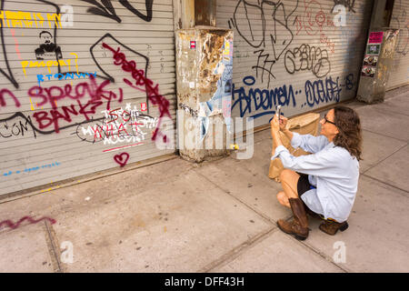 Zweite Tranche der Banksy-Graffiti-Kunst auf einer Rolle Tor im New Yorker Stadtteil Chelsea auf Donnerstag, 3. Oktober 2013, gemalt auf Mittwoch und bereits verwüstet. 'Das ist mein New York Akzent' Kunstwerk entstand durch die schwer fassbare Streetart-Künstler, die Werke in der Stadt, jeweils erstellen werden Tag, im Laufe des Monats Oktober. Die Schablonen sind begleitet von eine satirische aufgezeichnete Nachricht ein Museumsrundgang, die Sie hören können telefonisch unter der Nummer 1-800-656-4271 gefolgt von # und die Anzahl von Kunstwerken zu parodieren.  (© Richard B. Levine) Stockfoto