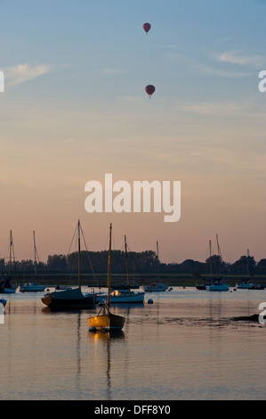 Zwei Heißluftballons am Himmel über Boote im Meer Stockfoto