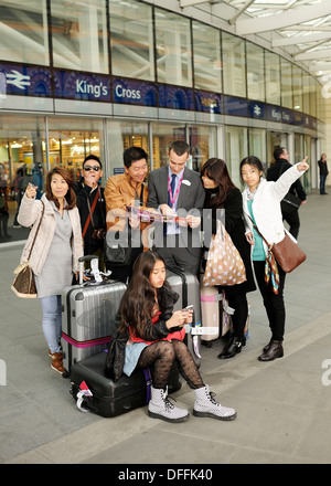 Chinesische Touristen immer Richtungen außerhalb Kings Cross Railway Station in London Stockfoto