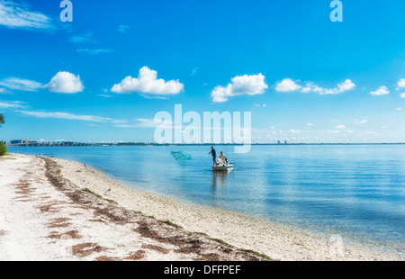 Zwei Männer Angeln bei Entfernung Cast net ins blaue Wasser der Golfküste von Florida blauen Himmel bewölkt. Weißen Sandstrand Küste. Stockfoto