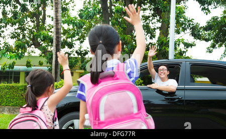 kleine Mädchen sagen auf Wiedersehen mit Vater vor Schule Stockfoto