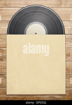 Alte Vinyl-Platte bei einem Papier auf Holztisch. Stockfoto