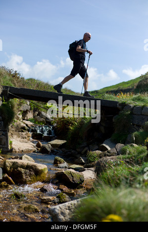 Rambler kreuzt eine Holzbrücke im Kinderbett-Tal, Porth Nanven in der Nähe von St. nur Cornwall UK Credit: David Levenson/Alamy Stockfoto