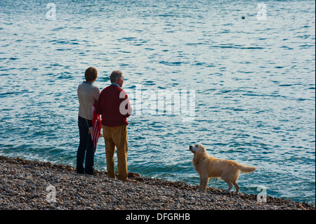 Mann und Frau mit Retriever Hund am Kiesstrand am Bier Devon UK Stockfoto