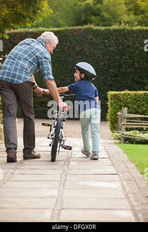 Großvater und Enkel Fahrrad auf Bürgersteig schieben Stockfoto