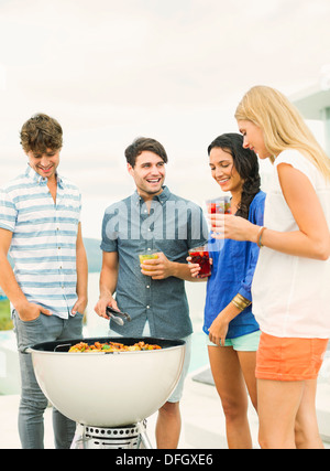 Freunde sprechen um Grill Stockfoto