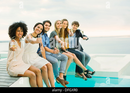 Freunde, toasten Sektgläser auf Fußgängerbrücke über Schwimmbad Stockfoto