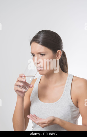 Brünette Frau, die Einnahme von Medikamenten mit einem Glas Wasser Stockfoto