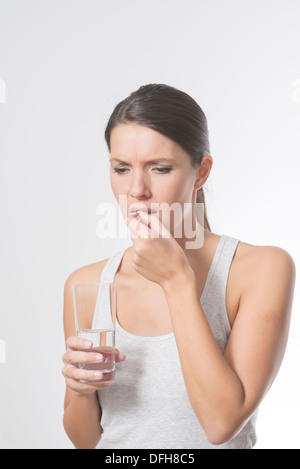 Brünette Frau, die Einnahme von Medikamenten mit einem Glas Wasser Stockfoto