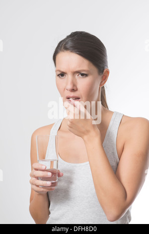 Brünette Frau, die Einnahme von Medikamenten mit einem Glas Wasser Stockfoto