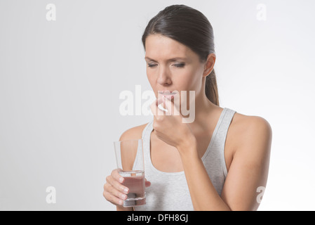 Brünette Frau, die Einnahme von Medikamenten mit einem Glas Wasser Stockfoto