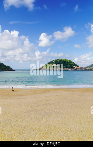 Einsamer Mann zu Fuß seinen Hund auf Playa de Ondarreta, mit Blick in Richtung Monte Urgull, San Sebastian, Spanien Stockfoto