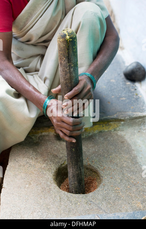 Inderin mit einem Mörser und Stößel um zu Spice außerhalb ihrer ländlichen Dorfhaus zu mahlen. Andhra Pradesh, Indien Stockfoto