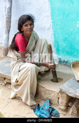 Inderin mit einem Mörser und Stößel um zu Spice außerhalb ihrer ländlichen Dorfhaus zu mahlen. Andhra Pradesh, Indien Stockfoto