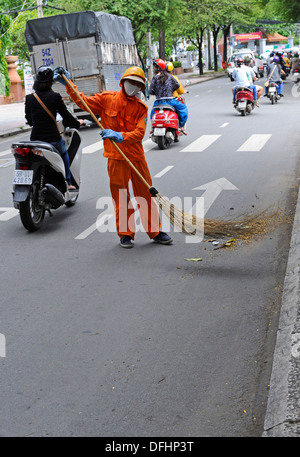Männliche Kehrmaschine auf einer belebten Straße in Ho-Chi-Minh-Stadt die Straßen fegen. Stockfoto
