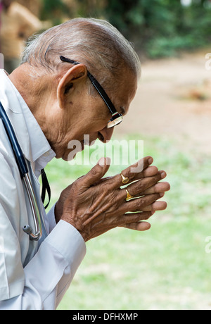 Indischer Arzt im Gebet am Sri Sathya Sai Baba mobile aufsuchende Hospital. Andhra Pradesh, Indien Stockfoto