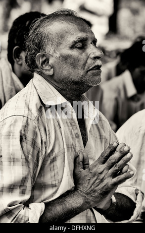 Indischer Mann im Gebet während der Wartezeit auf Sri Sathya Sai Baba mobile aufsuchende Krankenhaus zu sehen. Andhra Pradesh, Indien. Sepia Stockfoto