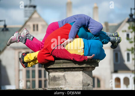 Bangor, Wales, UK. 5. Okt, erstellen 2013,20 bunt gekleidete junge Interpreten bunte statische Bilder, wie sie ihren Körper in Räume und Hohlräume in der Stadt Bangor in Nordwales einfügen. Österreichische Choreograf WILLI DORNER ersonnen, ist "Einrichtungen im urbanen Raum" eine weltweite Reisen Performance mit lokalen Tänzer und Turner. gequetscht und ausgewogen unter Architektur der Stadt. Hunderte von Menschen folgten ihren Fortschritt durch die Stadt auf eine einstündige kostenlose Leistung. Bildnachweis: Keith Morris/Alamy Live-Nachrichten Stockfoto