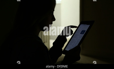 Silhouette eines jungen Mädchens mit einem digitalen Tablet mit offener Tür. Stockfoto